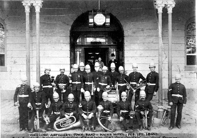 Black and white group portrait of the Geelong Artillery Town Band outside Mack's Hotel, February 13th 1890